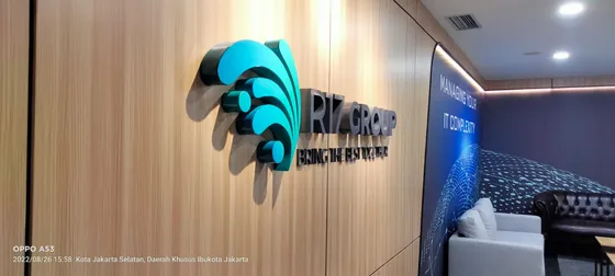 Huruf timbul akrilik biru dan logo perusahaan pada dinding kayu
