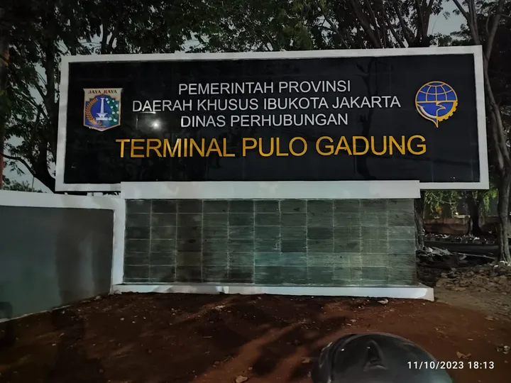 Huruf timbul tanpa lampu pada papan nama terminal, disinari lampu sorot dari luar pada malam hari