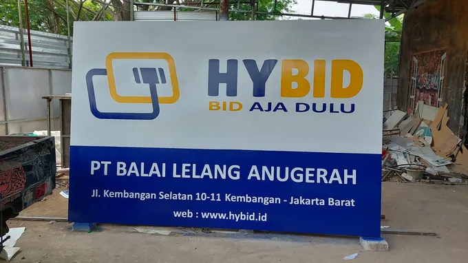 Signboard besar kantor balai lelang dengan panel biru dan putih