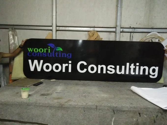 Signboard hitam kantor konsultan dengan huruf timbul putih