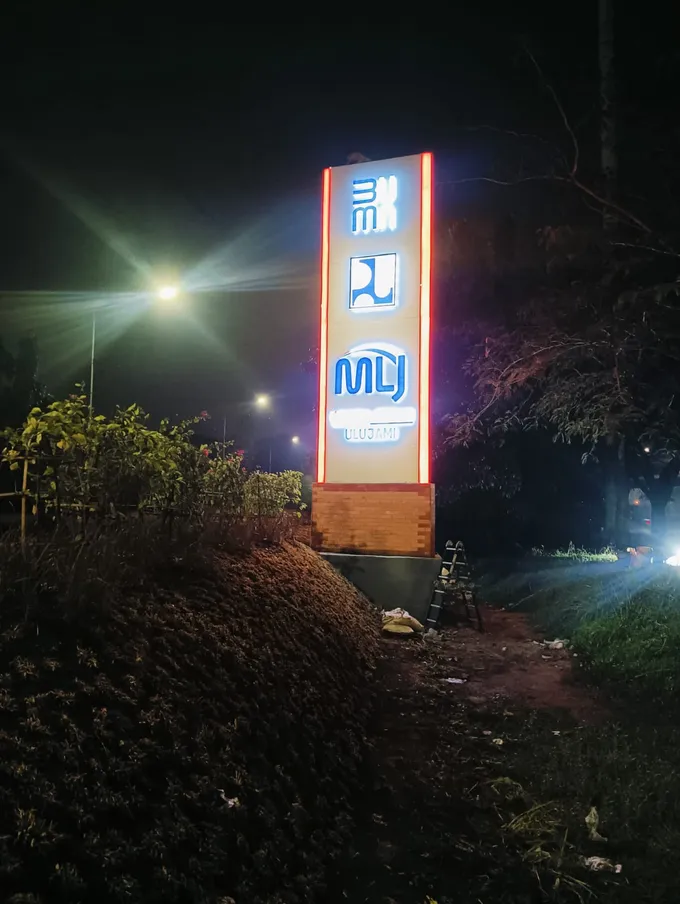 Pylon sign multi-tenant menyala terang pada malam hari