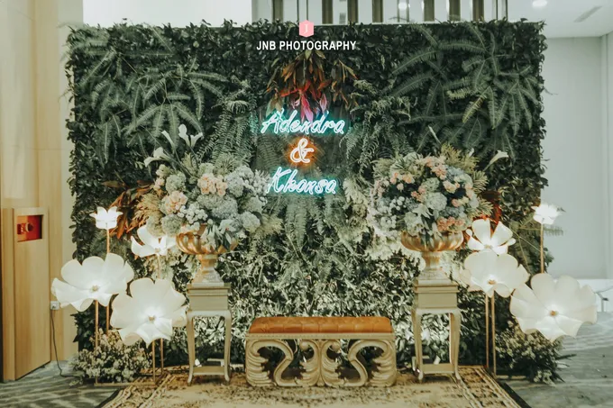 Nama pengantin dari neon flex pada backdrop bunga dekorasi acara